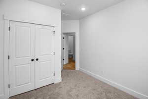 Unfurnished bedroom featuring light carpet and a closet