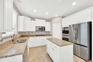 Kitchen featuring white cabinetry, sink, a center island, and appliances with stainless steel finishes