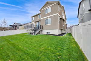 Back of house featuring a lawn and a deck