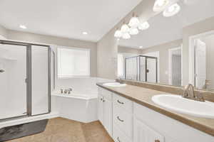 Bathroom featuring tile patterned floors, vanity, and shower with separate bathtub