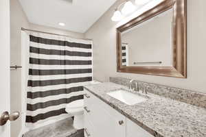 Bathroom featuring a shower with shower curtain, vanity, and toilet