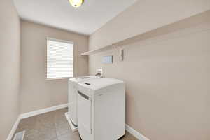 Laundry area with washing machine and clothes dryer and light tile patterned floors