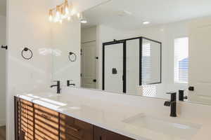 Bathroom with vanity, a shower with shower door, and plenty of natural light