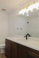 Bathroom featuring walk in shower, toilet, vanity, and hardwood / wood-style flooring