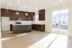 Kitchen featuring stainless steel appliances, a center island, a wealth of natural light, and pendant lighting