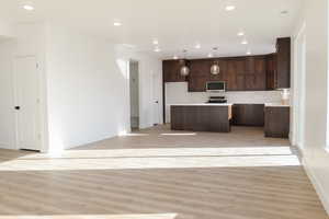 Kitchen featuring hanging light fixtures, light wood-type flooring, backsplash, and a kitchen island