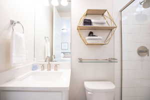 Bathroom featuring vanity, toilet, and an enclosed shower