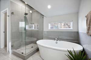 Bathroom featuring independent shower and bath and tile walls