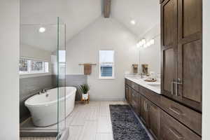 Bathroom with vaulted ceiling with beams, a bath, tile patterned floors, vanity, and tile walls