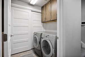 Laundry area featuring washer and clothes dryer, cabinets, and light hardwood / wood-style flooring