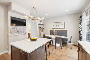 Kitchen featuring a center island, hanging light fixtures, light hardwood / wood-style flooring, a breakfast bar area, and a chandelier