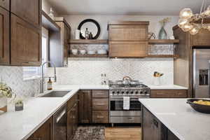 Kitchen with backsplash, sink, light stone countertops, light wood-type flooring, and stainless steel appliances