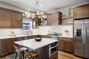 Kitchen featuring a center island, sink, appliances with stainless steel finishes, light hardwood / wood-style floors, and a breakfast bar area