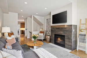 Living room featuring a tiled fireplace and wood-type flooring