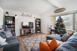 Living room featuring vaulted ceiling with beams and light hardwood / wood-style floors