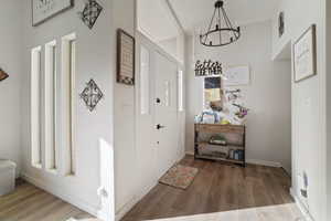 Corridor featuring wood-type flooring and an inviting chandelier