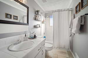 Full bathroom featuring vanity, shower / bath combination with curtain, crown molding, tile patterned flooring, and toilet