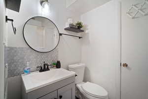 Bathroom with vanity, backsplash, and toilet