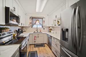 Kitchen with white cabinetry, backsplash, and appliances with stainless steel finishes