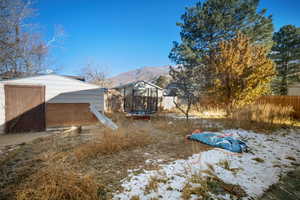 Yard layered in snow featuring a mountain view and a trampoline