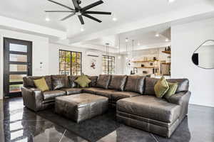 Living room with a raised ceiling, a wall unit AC, ceiling fan, and sink