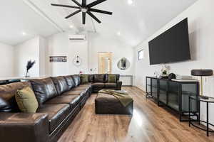 Living room featuring an AC wall unit, vaulted ceiling with beams, ceiling fan, and light wood-type flooring