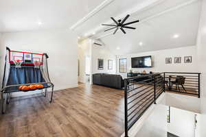 Interior space featuring vaulted ceiling with beams, hardwood / wood-style flooring, a wall unit AC, and ceiling fan