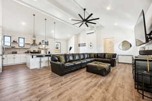 Living room with ceiling fan, sink, light hardwood / wood-style flooring, a wall mounted AC, and vaulted ceiling