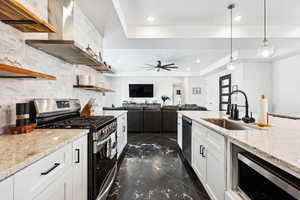 Kitchen featuring sink, a tray ceiling, decorative light fixtures, white cabinetry, and stainless steel appliances