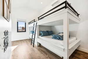 Bedroom with vaulted ceiling, wood-type flooring, and a wall mounted AC