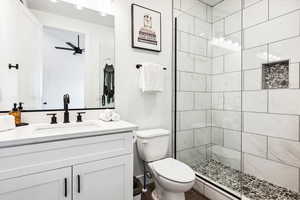 Bathroom featuring vanity, toilet, and a tile shower