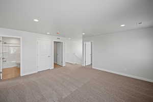 Unfurnished bedroom featuring connected bathroom and light colored carpet