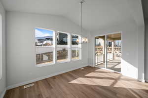 Unfurnished dining area featuring a chandelier, hardwood / wood-style flooring, and vaulted ceiling