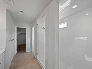 Bathroom featuring tile patterned flooring, vanity, and a tile shower