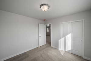 Unfurnished bedroom featuring light carpet and a closet