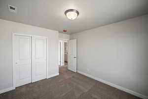 Unfurnished bedroom featuring dark colored carpet and a closet