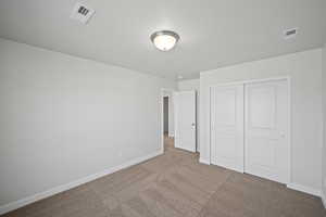 Unfurnished bedroom with light carpet and a closet