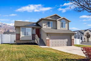 Tri-level home featuring a mountain view, a front lawn, and a garage