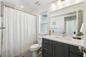 Bathroom featuring tile patterned floors, vanity, toilet, and a healthy amount of sunlight