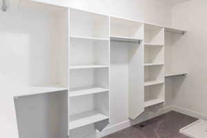 Spacious closet with dark carpet