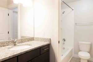 Full bathroom with vanity, tile patterned floors,  shower combination, and toilet