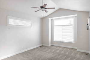 Spare room featuring ceiling fan, light colored carpet, and vaulted ceiling