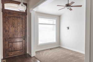 Foyer entrance with ceiling fan and dark wood-type flooring