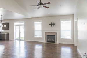 Unfurnished living room featuring a fireplace, a wealth of natural light, lofted ceiling, and ceiling fan