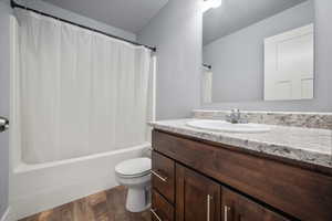 Full bathroom with shower / bath combo with shower curtain, toilet, vanity, and LVP flooring