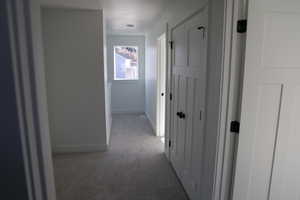 Hallway featuring light carpet