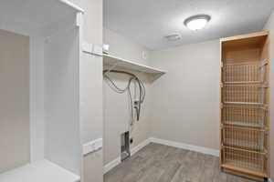 Laundry area featuring hardwood / wood-style floors, electric dryer hookup, and a textured ceiling