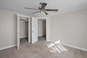 Unfurnished bedroom with ceiling fan, light carpet, and a textured ceiling