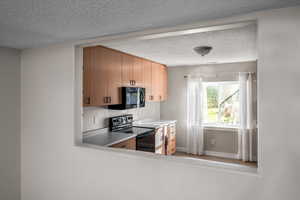 Kitchen with electric stove and a textured ceiling