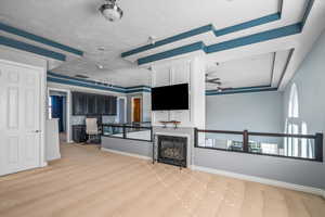 Living room with light colored carpet, ceiling fan, and a tray ceiling